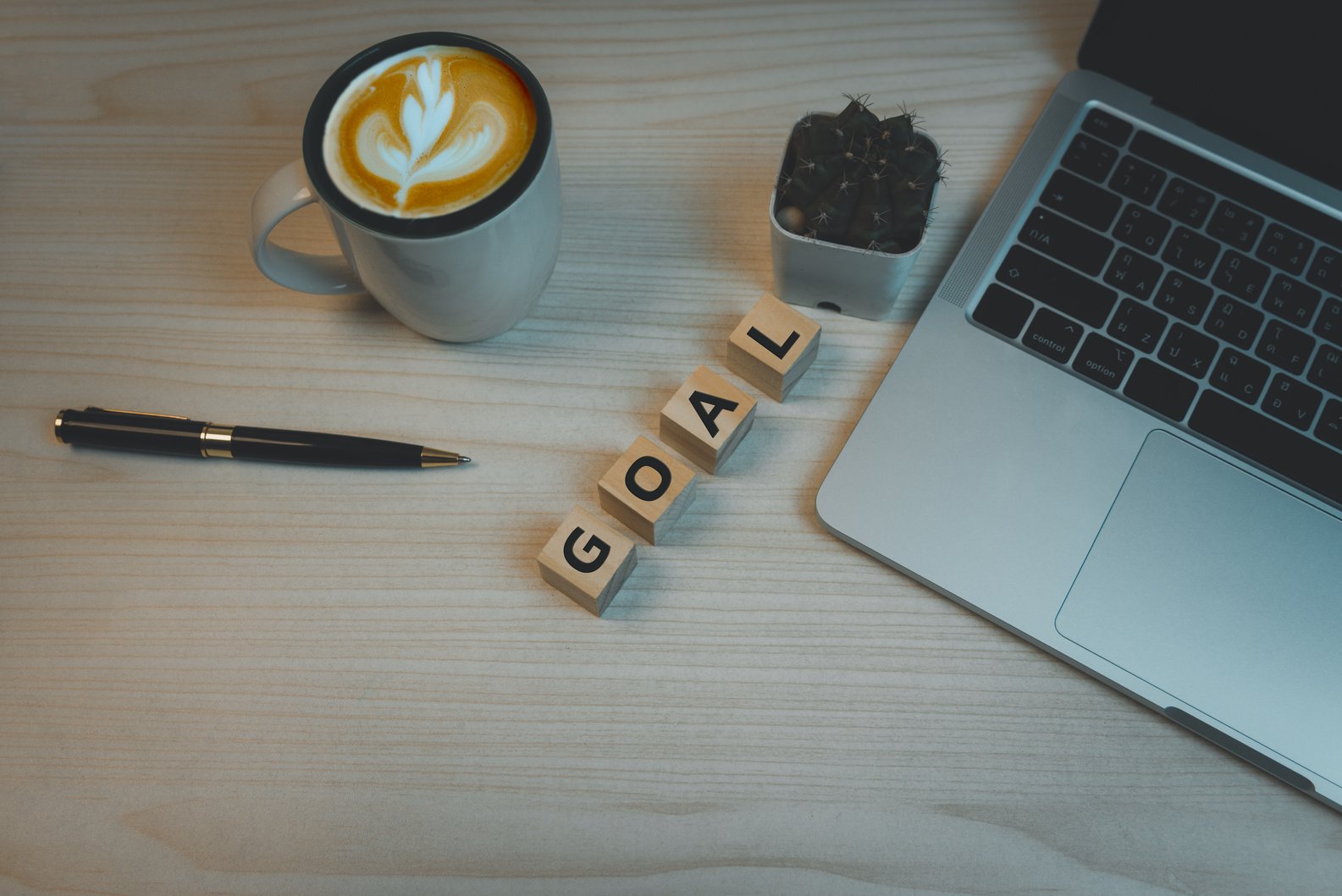 Wood cube block goal and pen coffee with computer laptop on table top view background.Copy space business idea plan success concept.